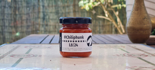 1 Glas Chilipaste Chiliphunk "L8/24" mit 9 Sternen am Etikett, auf einem Holztisch.